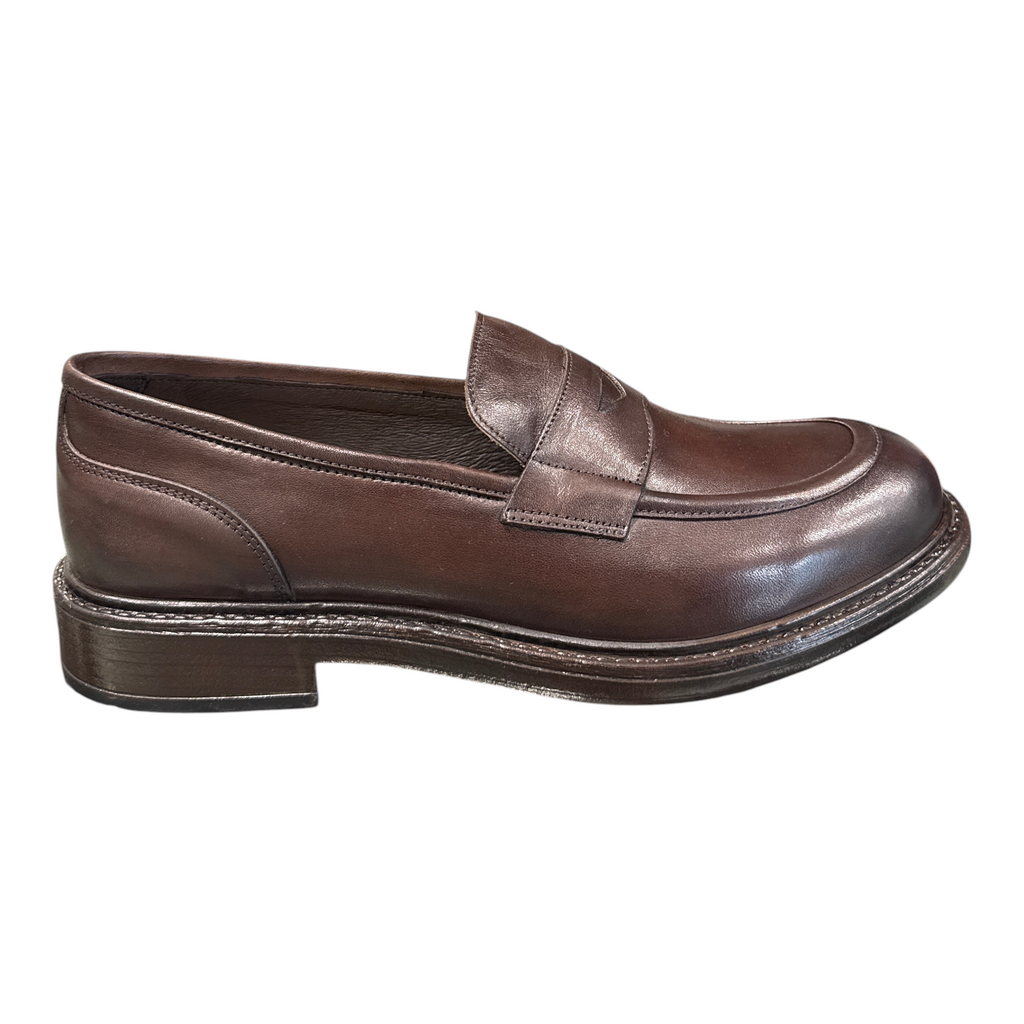 Mocassino da uomo NEED in pelle color castagno con design classico e suola robusta esposto su un ripiano in negozio